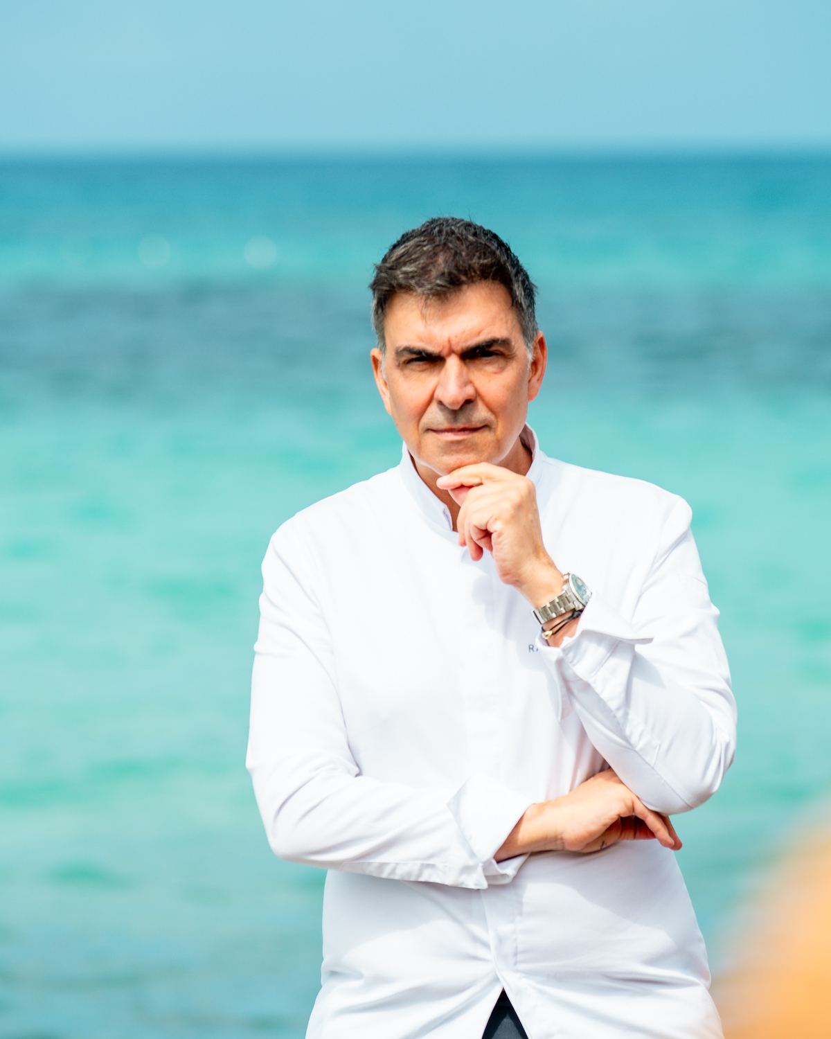 Ramón Freixa con chaquetilla blanca frente al agua turquesa de Cala Saona